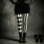 A circus performer wears velvet broomer with black and white jester tights with classic victorian boots