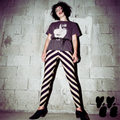 Model posing in black and cream diagonal stripe leggings with a post-punk aesthetic, styled with a leather jacket and Siouxsie Sioux graphic tee.