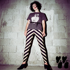 Model posing in black and cream diagonal stripe leggings with a post-punk aesthetic, styled with a leather jacket and Siouxsie Sioux graphic tee.
