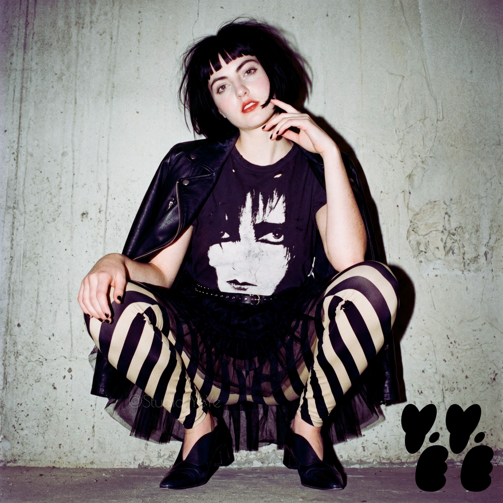 Model posing in black and cream diagonal stripe leggings with a post-punk aesthetic, styled with a leather jacket and Siouxsie Sioux graphic tee.