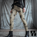 Model wearing skull beige vintage anatomical leggings with skulls, brains, and other anatomical illustrations, styled with black boots.