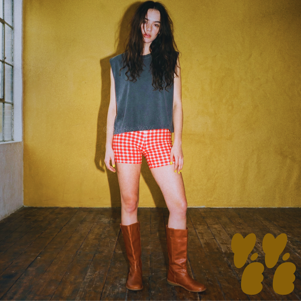 A female model wears red gingham check bike shorts with oversized T-shirts with vintage brown long boots