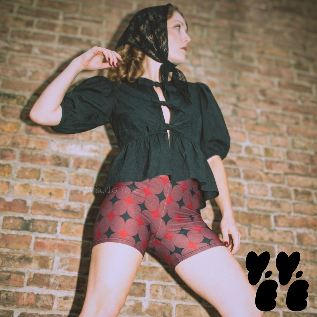 A vintage circus core style model wears mid century style diamond pattern bike shorts with puff sleeve tops