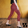 Model wearing flamingo pink leopard print capri leggings with black heels and a black top against a vintage gold backdrop.