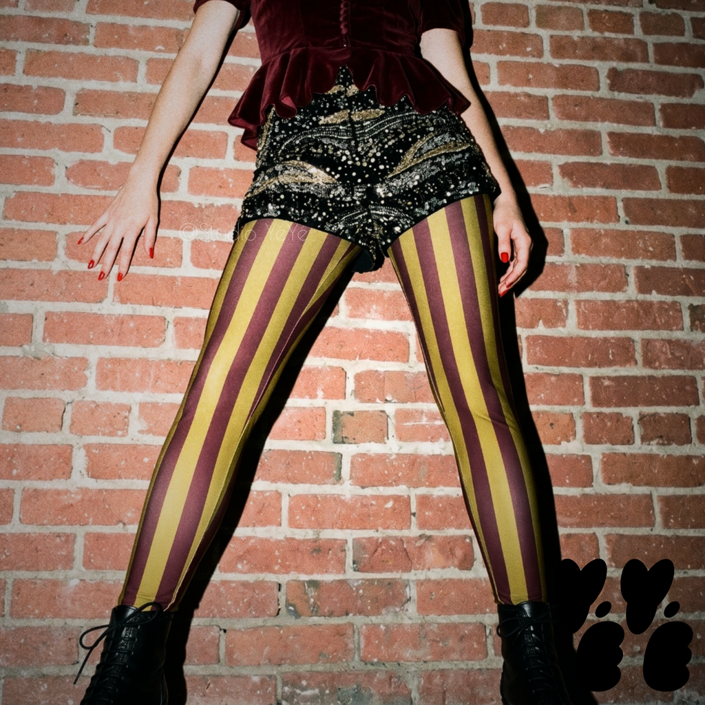 Circus Circus leggings in burgundy and gold vertical stripes by Studio YéYé, styled with sequin shorts and black ankle boots.