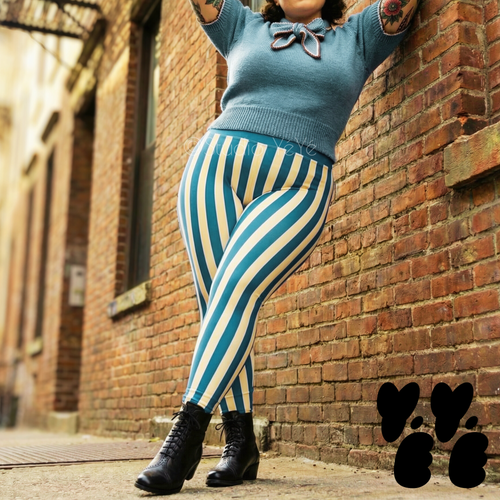 A plus sized female model wears size 3XL circus stripe leggings in blue and white, with 50s vintage sweater and short boots