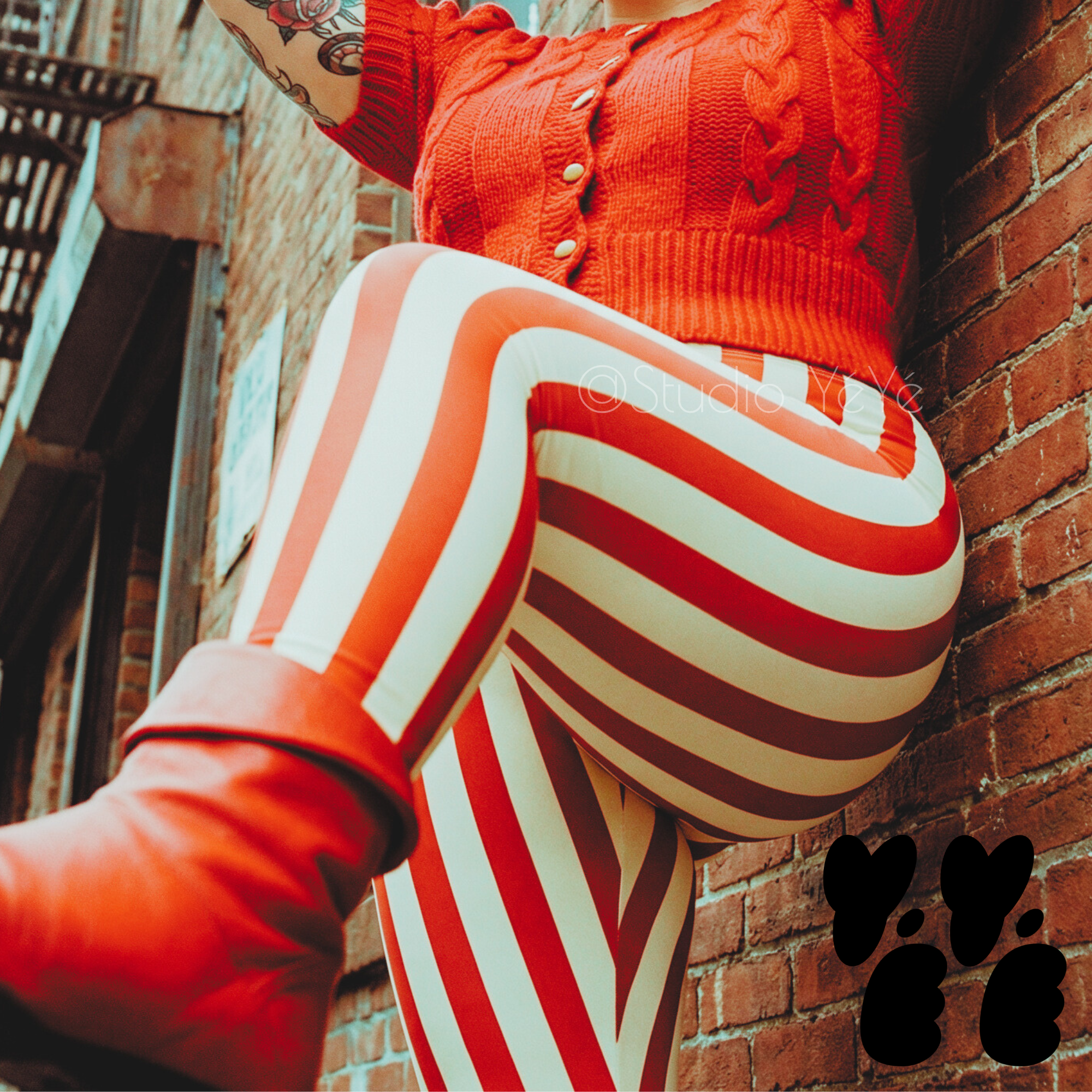 A plus size female model wears 3XL circus stripe leggings in red and white, with vintage red boots and short sleeve sweater