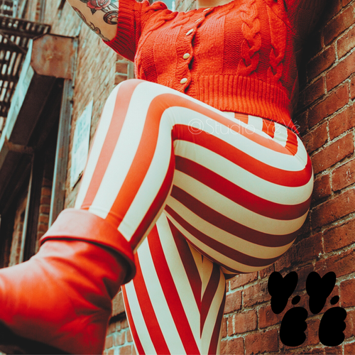 A plus size female model wears 3XL circus stripe leggings in red and white, with vintage red boots and short sleeve sweater