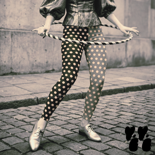 Mismatched grayscale polka dot leggings in black and grey by YéYé, styled with a silver metallic puff sleeve top and silver oxford shoes, hula hoop on cobblestone street