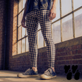 a male model wears vintage black t-shirts with gingham check printed leggings in black and white, with vintage converse shoes