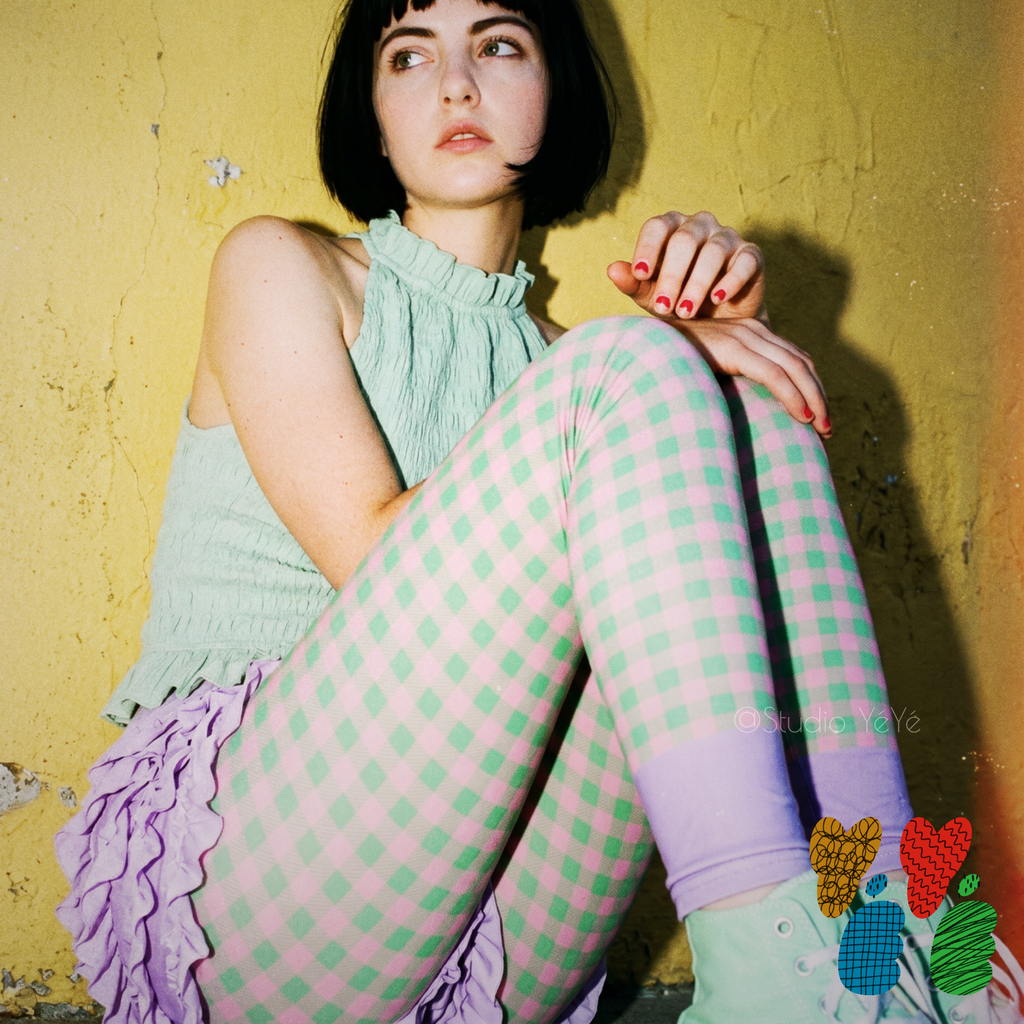Mint and pink gingham leggings with lavender colour-blocked ankle by YéYé, styled with a mint smocked halter top and lavender ruffle skirt against a yellow wall