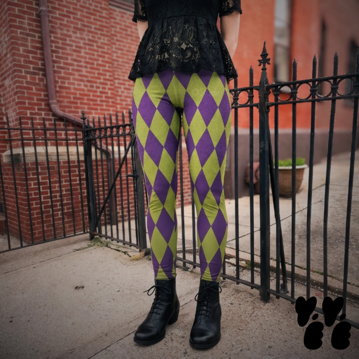 Model wearing purple and acid green harlequin diamond leggings with a black lace top and black boots.