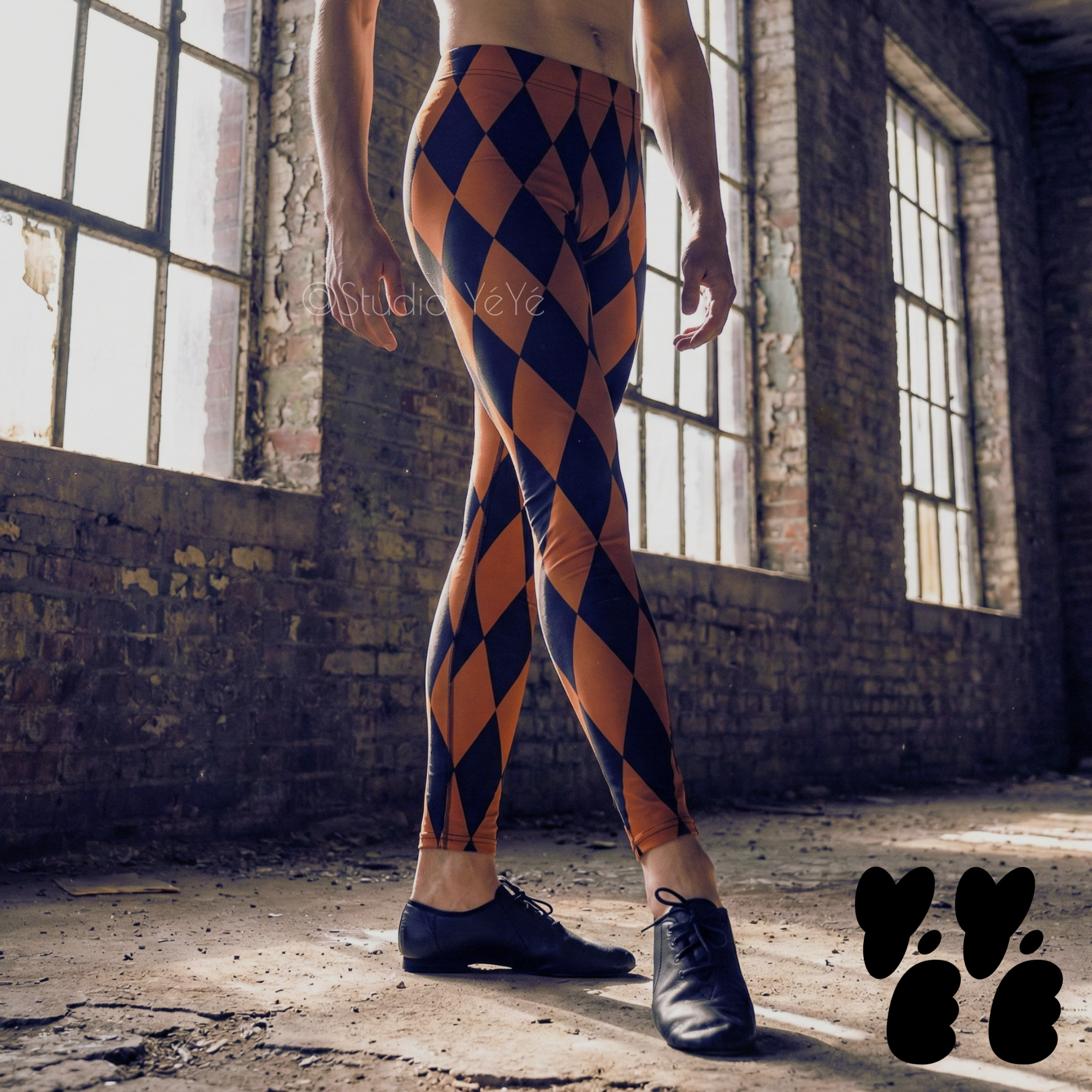 Burnt orange and black harlequin diamond mens leggings by YéYé, styled with black jazz shoes in an industrial warehouse