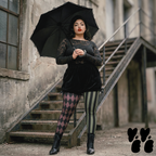 A plus size model wears black broomer, vintage lace top with jester leggings in olive and maroon, with victorian boots, goth punk vibe.