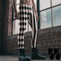black and white harlequin diamond and stripe mens leggings by YéYé, styled with black combat boots in front of industrial windows