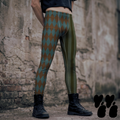 Brown and teal harlequin diamond and olive stripe mens leggings by YéYé, styled with a black crop tee and black combat boots against a stone wall