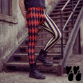 Red and black harlequin diamond and cream stripe mens leggings by YéYé, styled with a dark grey crop tee and black lace-up boots on metal stairs