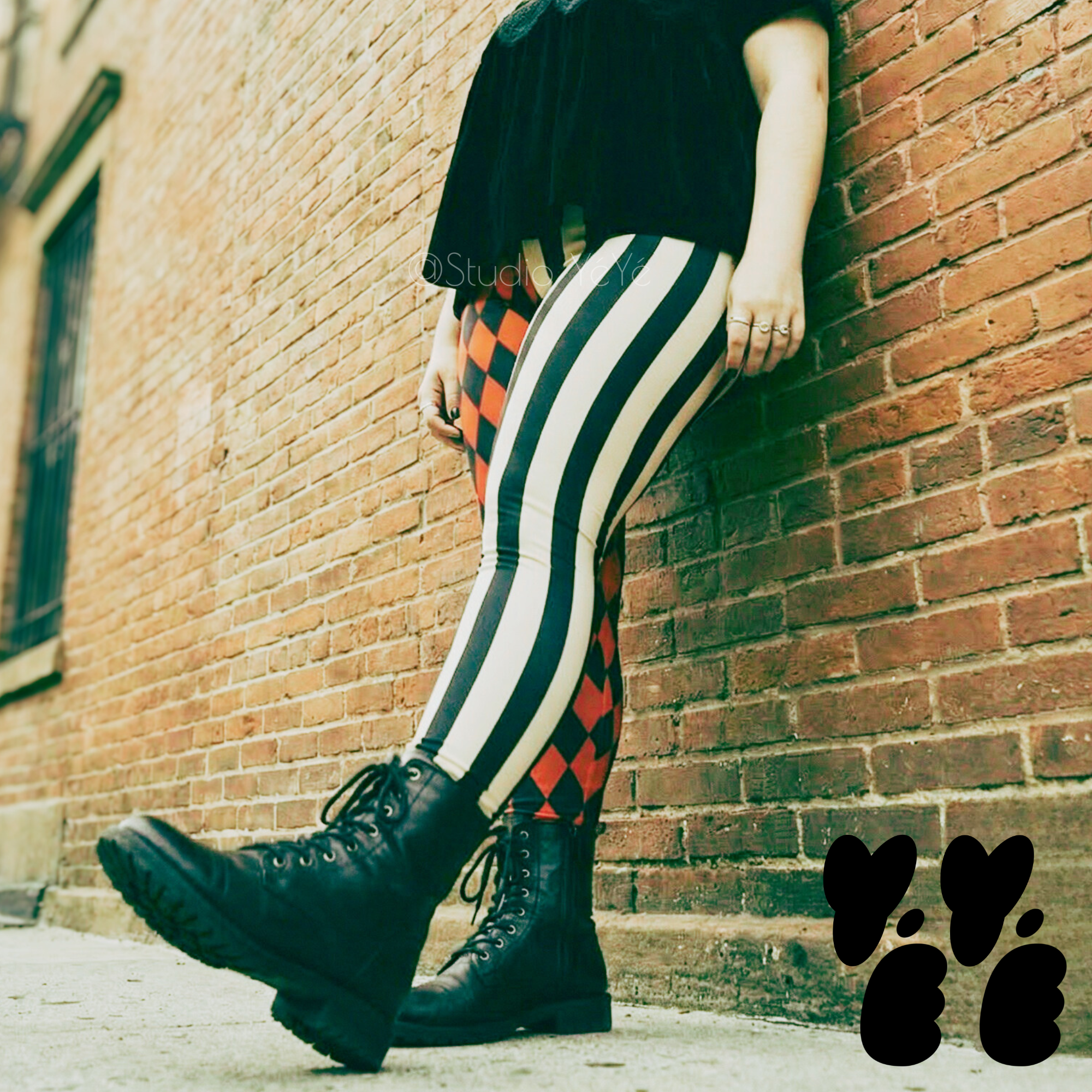 A plus sized female model wears harlequin jester leggings with combat boots
