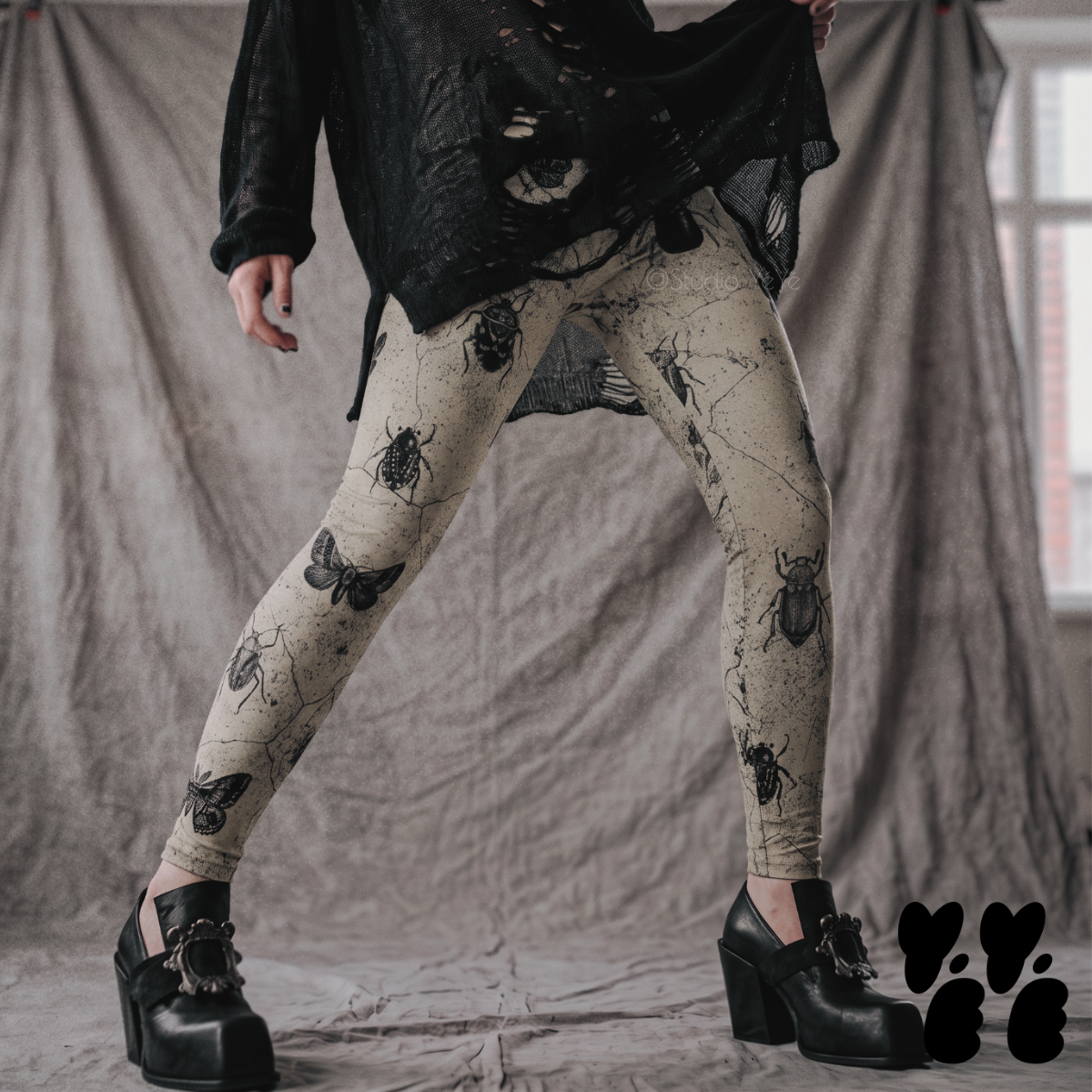 Model wearing beige vintage-inspired leggings covered with black beetles, moths, and insect illustrations, styled with black boots.