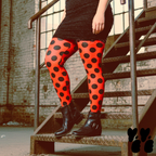 A plus sized female model wears 2XL large polka dot leggings in red and black, wears glitter mini dress and vintage boots