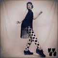 A flapper fashion girl wears 1930s vintage dress with large polka dot leggings with black platform shoes, posing like flapper dancer.