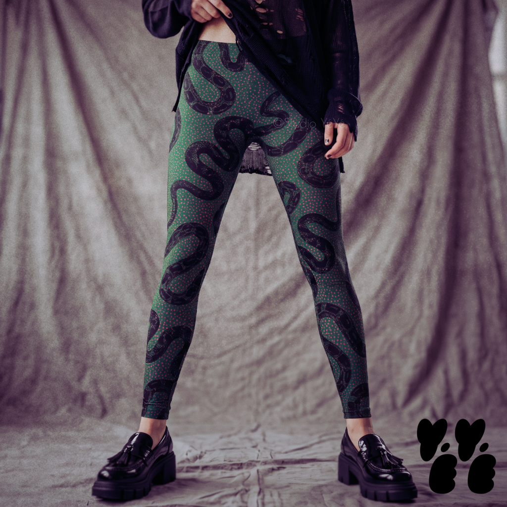 Model wearing dark green leggings with vintage black snake illustrations and hot pink dots, styled with a dark purple top and platform loafers.