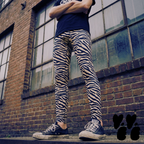 A male model wears tiger pattern leggings for men in off white with converse shoes.