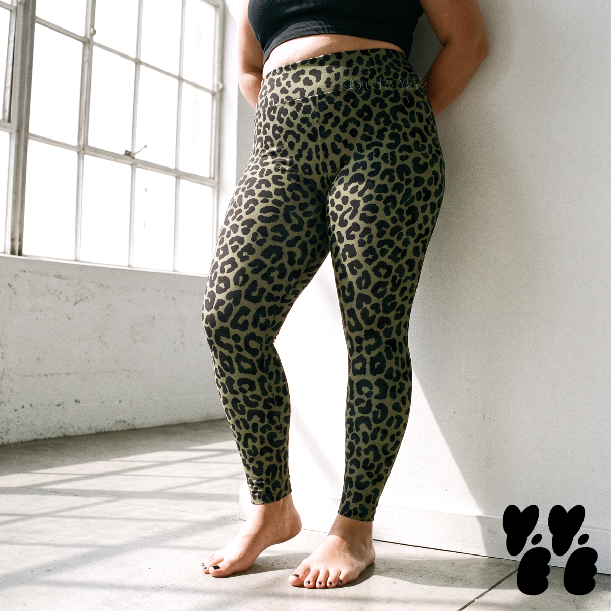 A plus size woman wears leopard high waist leggings in olive green and black.