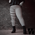 Model wearing black and white harlequin diamond and fine pinstripe leggings with a black lace top and black boots.