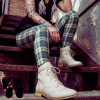 Green and cream tartan plaid leggings by YéYé, styled with a black mini skirt and cream lace-up brogue boots on rusty metal stairs