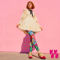Vintage Rococo floral print leggings by YéYé in vibrant blue, red and green, styled with a cream lace mini dress, black ribbon choker and two-tone oxford shoes against a pink wall