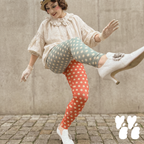 Mismatched polka dot leggings in sage green and terracotta by YéYé, styled with a cream ruffle blouse, lace gloves, beige beret and jewelled kitten heels on cobblestone