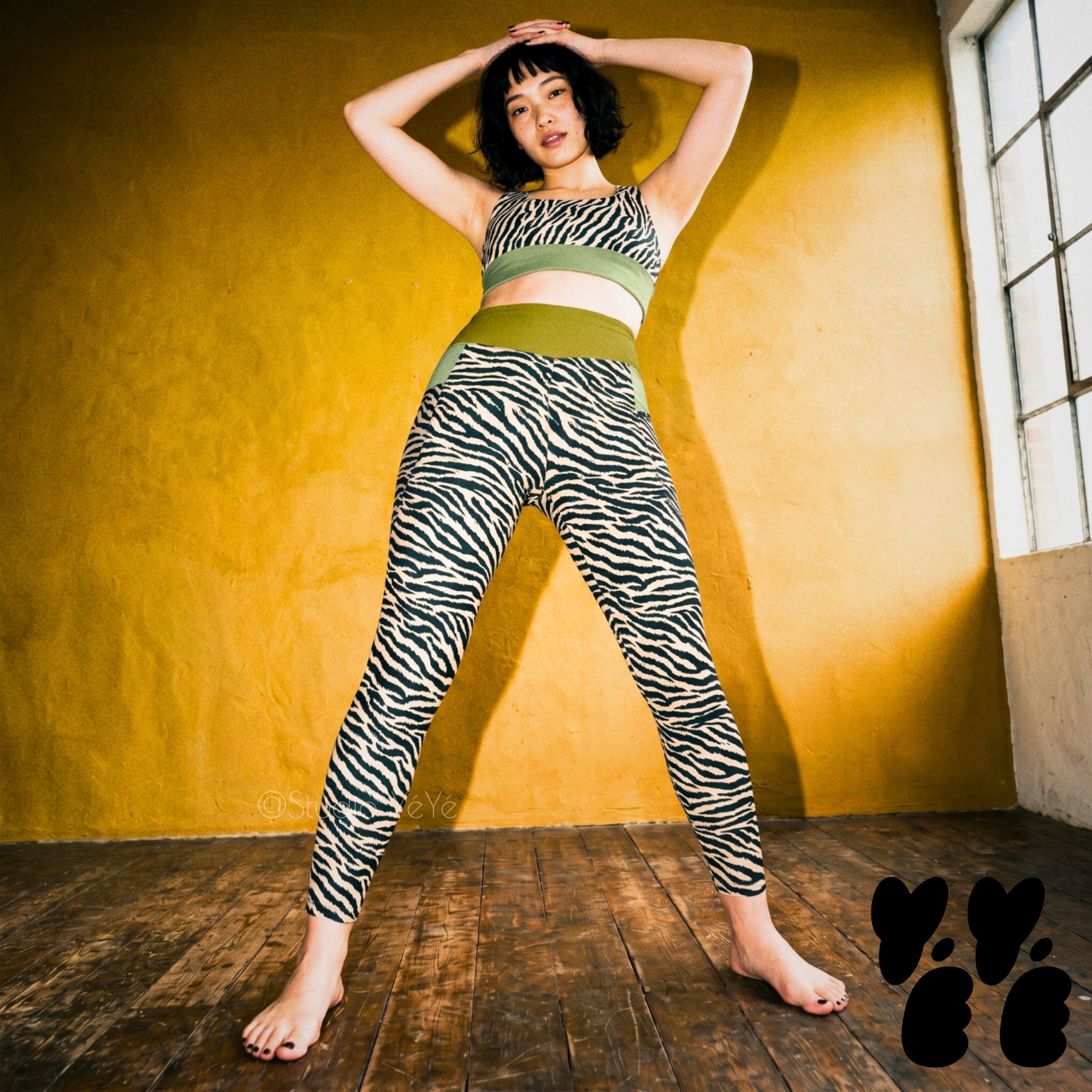 A japanese young woman wears zebra - tiger printed yoga pocket leggings with matching bra at cool yoga studio. 