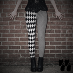 Model wearing black and white harlequin diamond and fine pinstripe leggings with a black lace top and black boots.