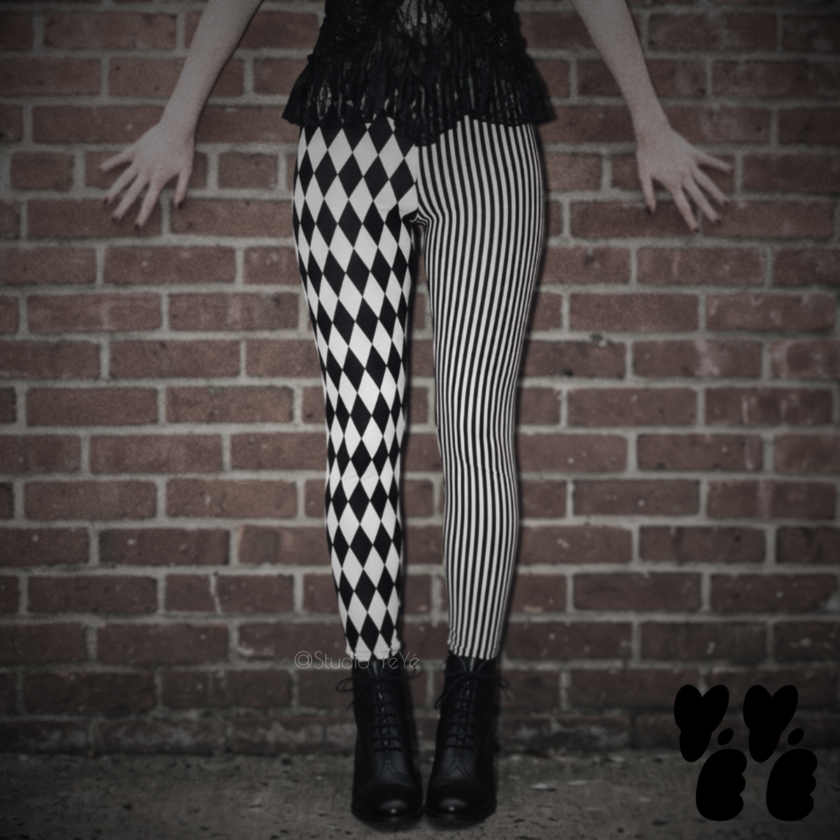 Model wearing black and white harlequin diamond and fine pinstripe leggings with a black lace top and black boots.