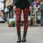 Red tartan plaid leggings by YéYé, styled with a black mini dress, black leather jacket and olive green lace-up combat boots on a city street