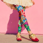 Vintage Rococo floral print leggings by YéYé in vibrant blue, red and green, styled with a cream lace mini dress, black ribbon choker and two-tone oxford shoes against a pink wall
